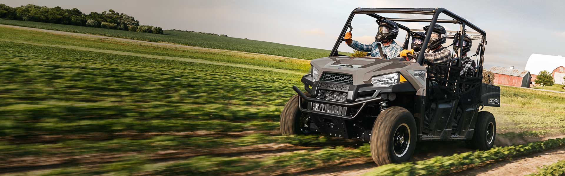 Group of people riding in a 2019 Polaris® Ranger Crew UTV through farmland.